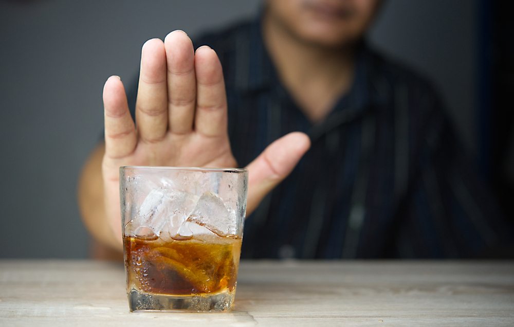 Alcoholism treatment concept.Man refuses to drink a alcohol.shutterstock_1511504006